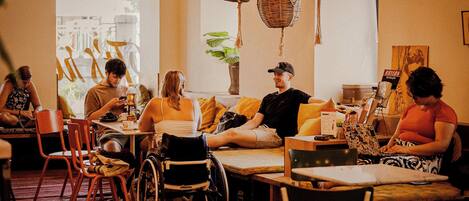 A cozy indoor seating area with tables, chairs, and a wheelchair.