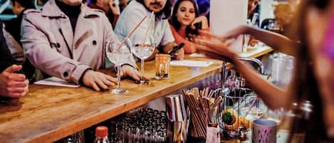 Una zona de bar con mostrador de madera, vasos y botellas.