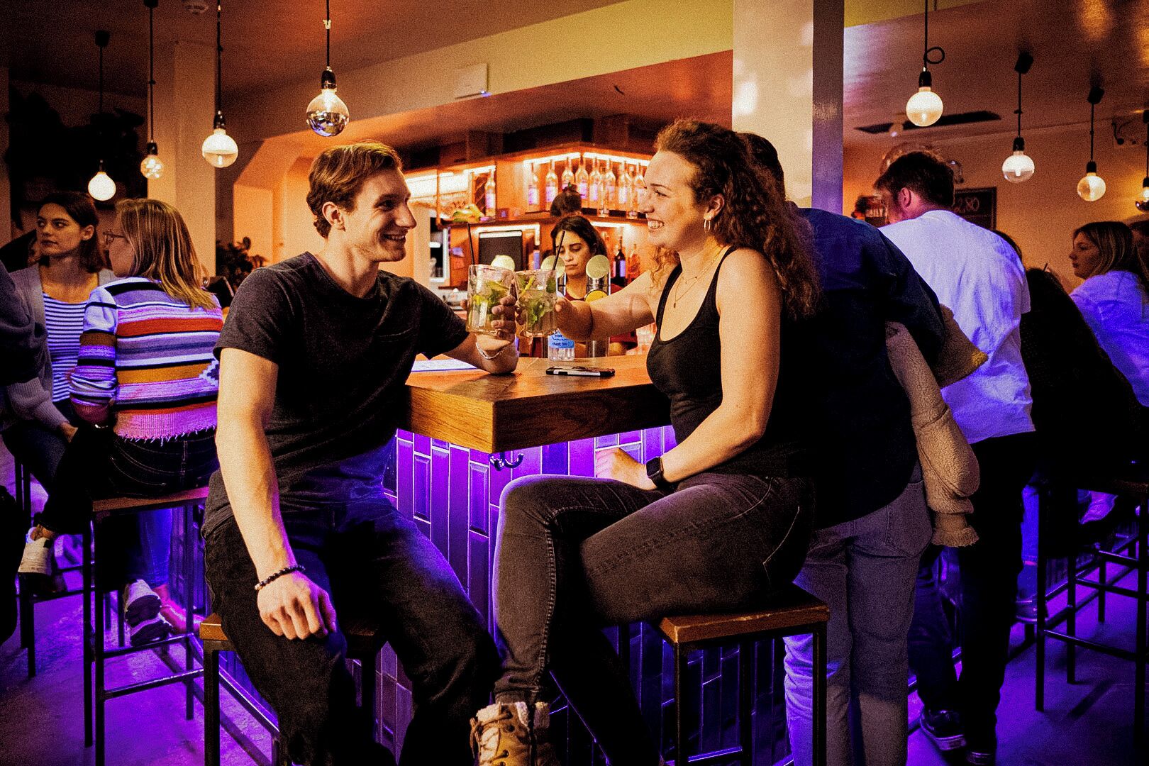 A bar with stools and hanging light fixtures.