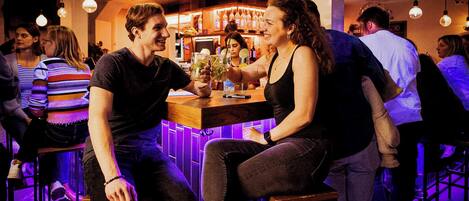 Um bar com banquetas e luminárias pendentes.