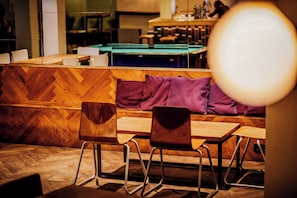 A modern interior with wooden flooring, a pool table, and seating areas with chairs and cushions. - Wombat's City Hostel Vienna Naschmarkt (Vienna)