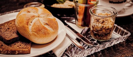 A table with a loaf of bread, a glass of iced coffee, and a jar of granola.