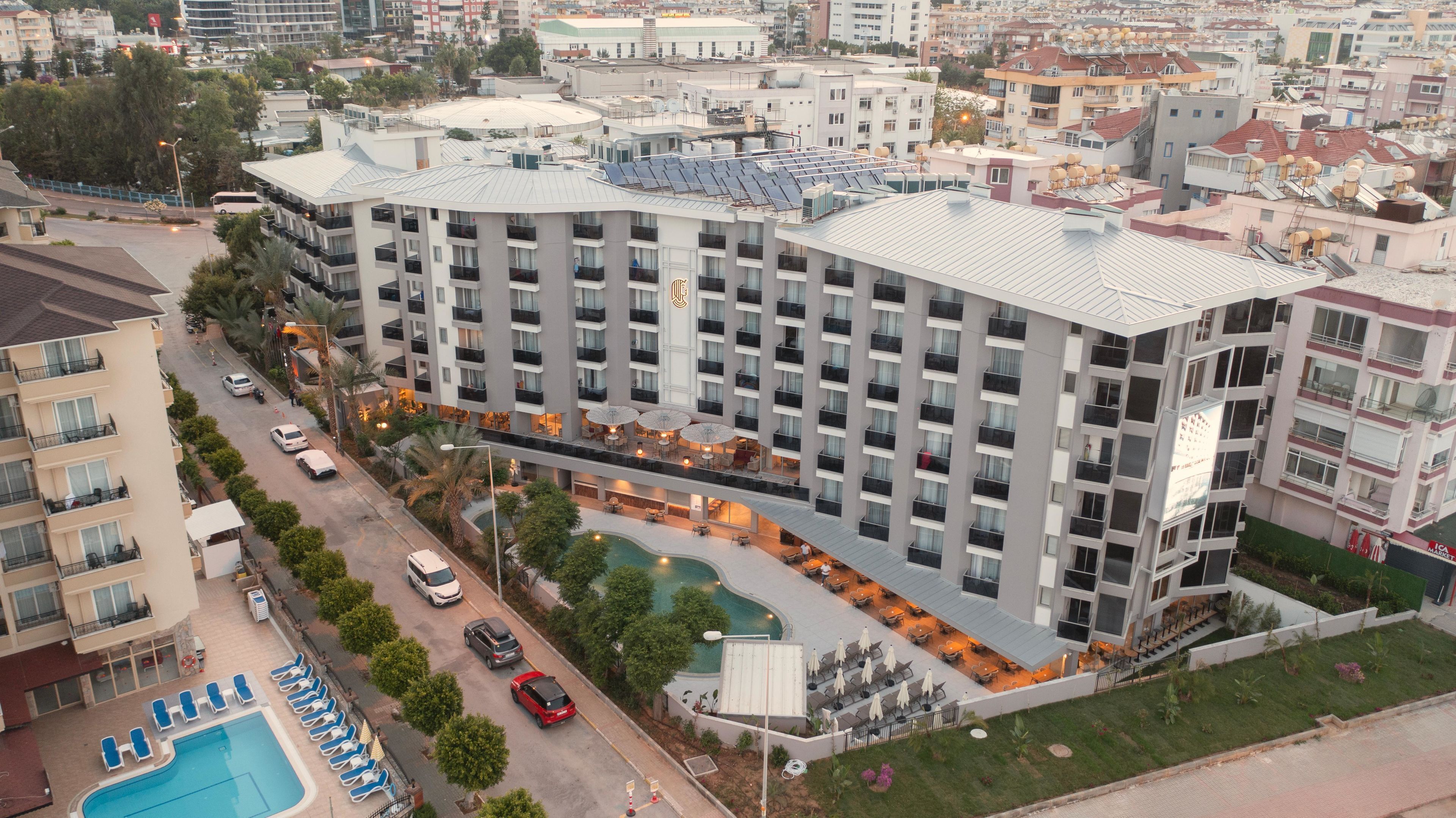 A multi-story hotel with a rooftop pool, outdoor seating, and a swimming pool.