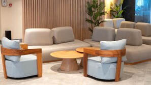 Uma sala de estar moderna com um sofá seccional, duas cadeiras de madeira e uma mesa de centro redonda de madeira.