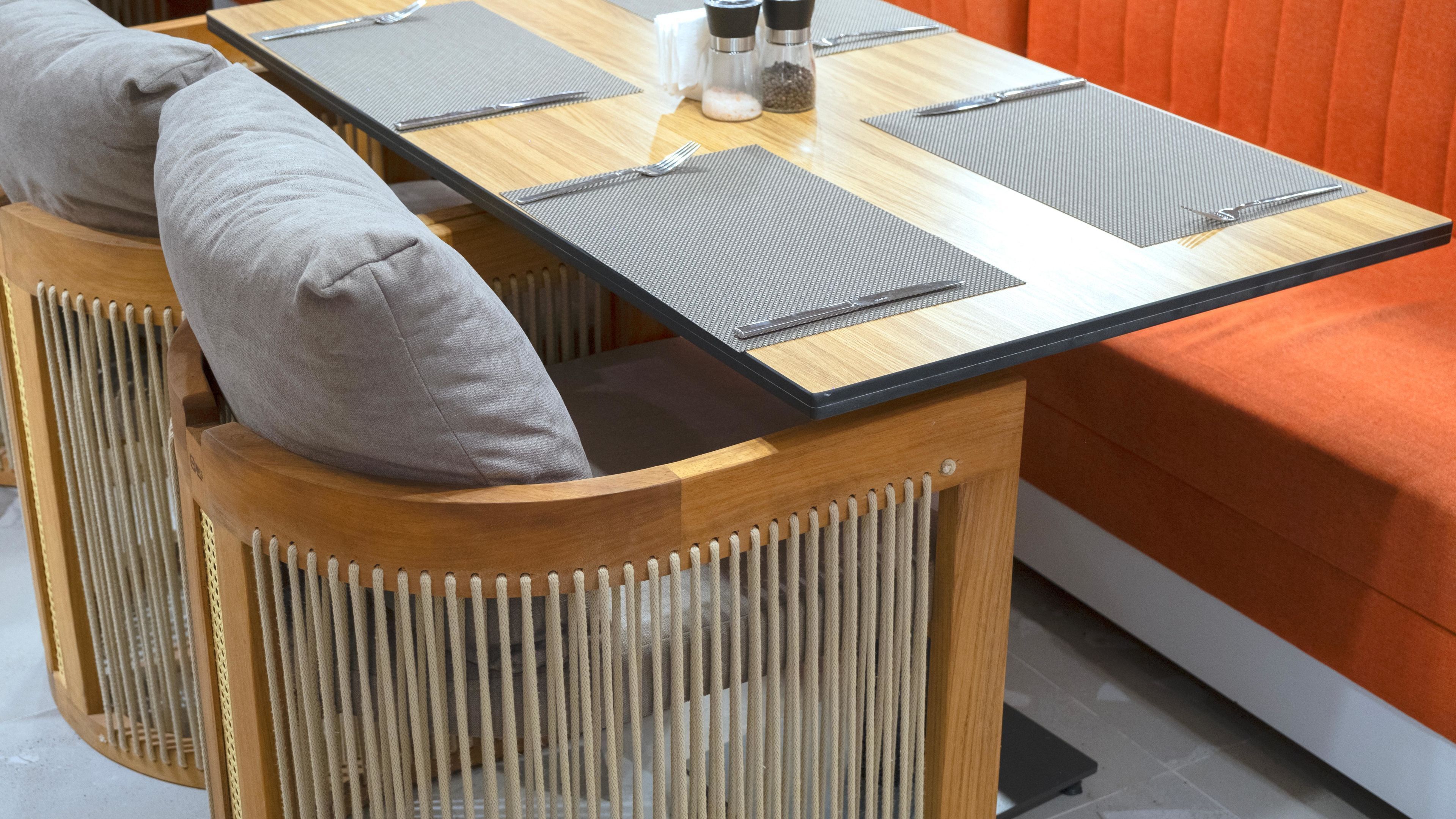 A corner table with a black top, grey placemats, and salt and pepper shakers.