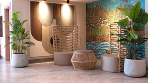 Un vestíbulo con un gran mural en la pared, una silla tejida y plantas en macetas.