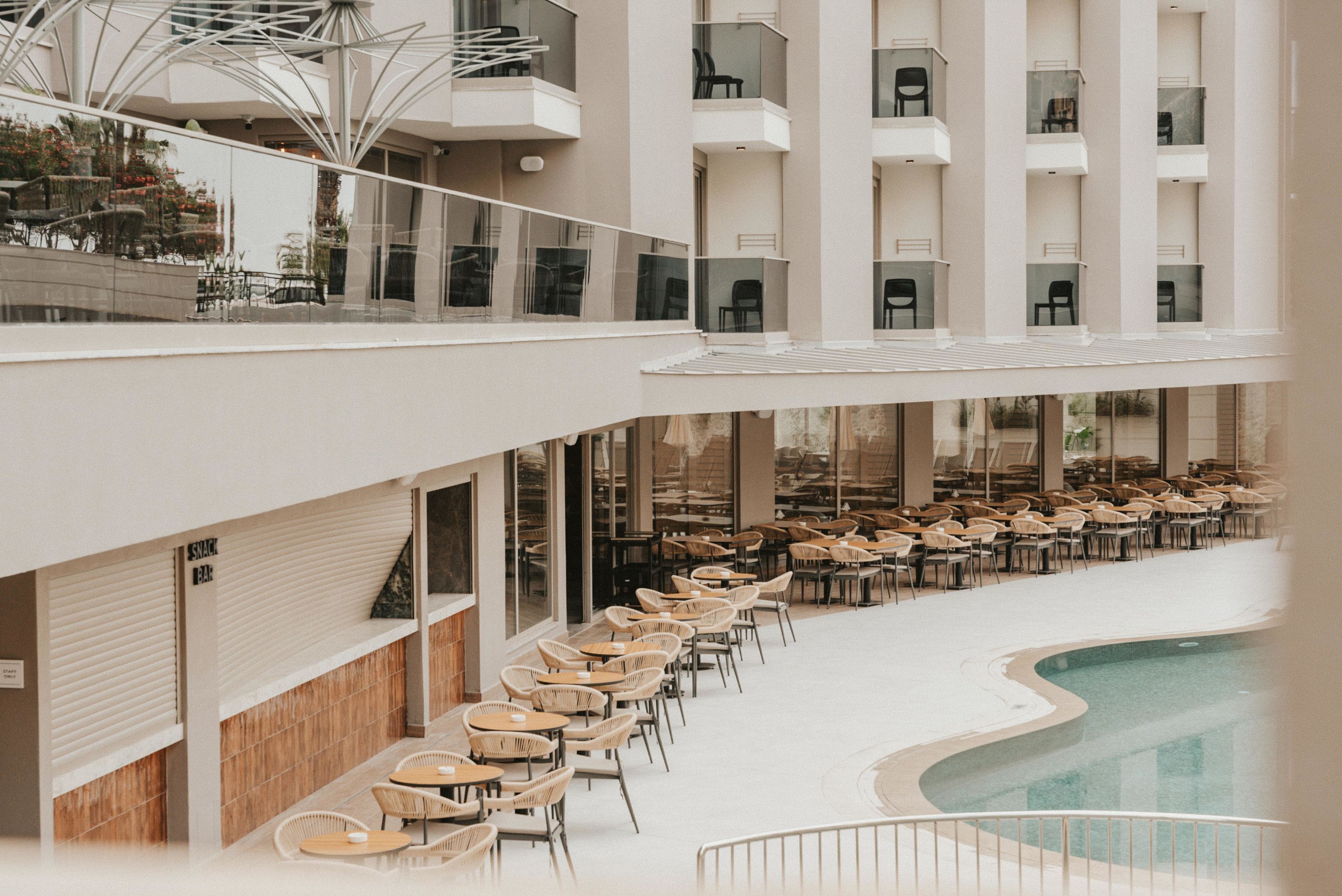 A modern hotel with a pool area, multiple floors, and outdoor seating.