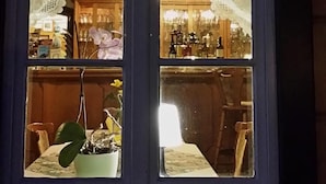 A window with a view of a room containing a table, chairs, and a potted plant. - Sonnebergbaude Waltersdorf (Grossschoenau)