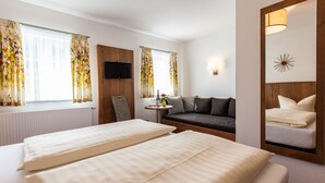 A hotel room with two beds, a sofa, a TV, and a mirror. - Sonnebergbaude Waltersdorf (Grossschoenau)