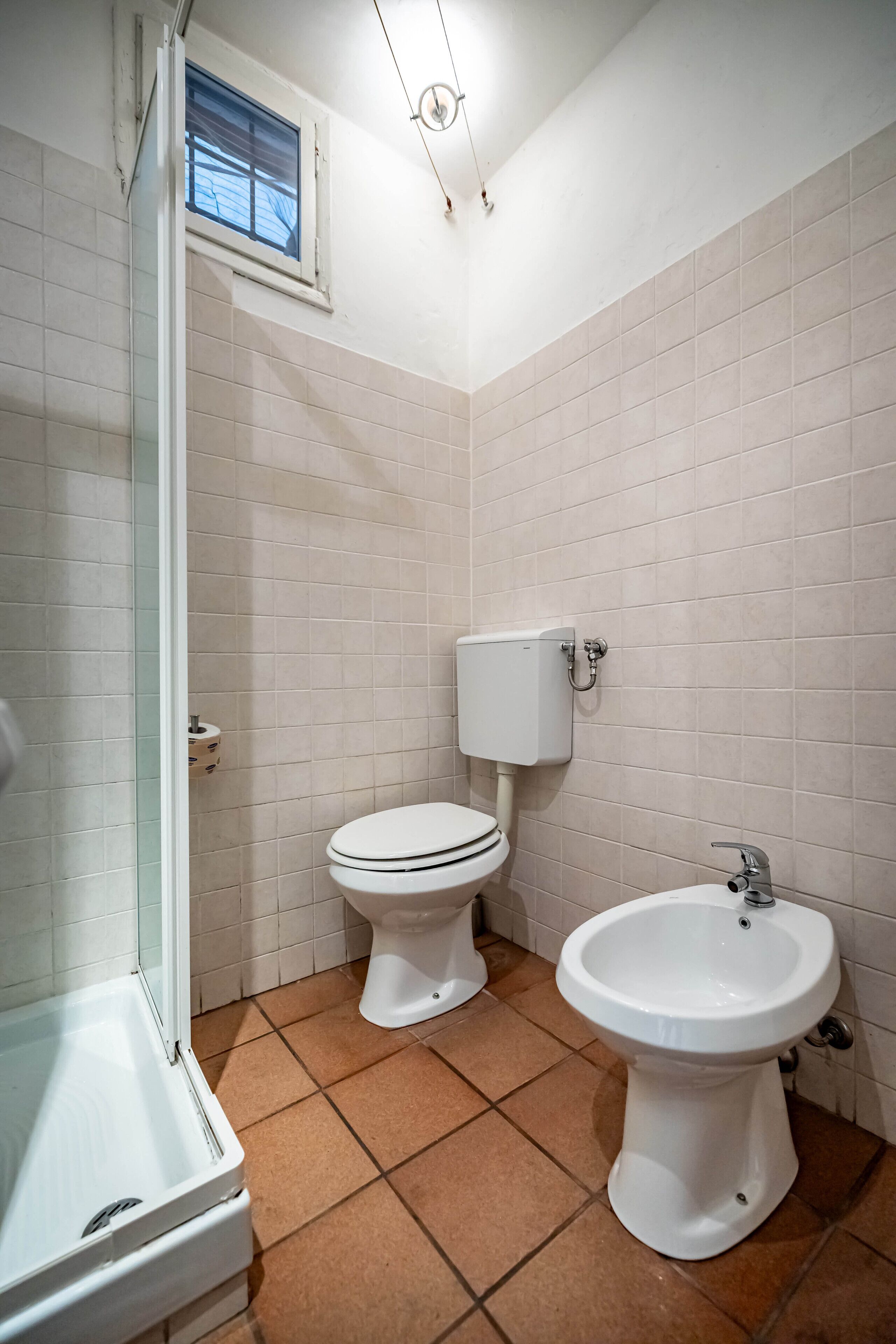 A bathroom with a toilet, bidet, and shower.