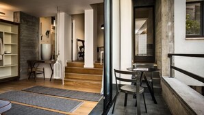 Un intérieur moderne avec un escalier menant à un deuxième étage, un coin repas avec une table et des chaises, et un couloir avec un porte-manteau et des étagères.