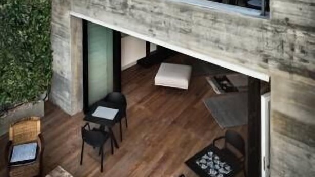 Un bâtiment moderne à deux étages, doté d’un balcon, de planchers en bois et d’un mur végétal.
