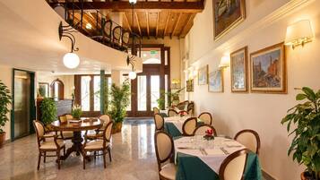 Ein Restaurantbereich eines Hotels mit mehreren Tischen, Stühlen und einer Treppe.