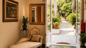 A lobby with a sofa, a mirror, a framed painting, and a potted plant. - Hotel Hieracon (Carloforte)