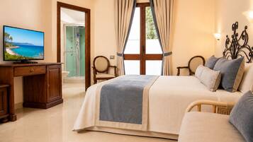 Ein Hotelzimmer mit Bett, Schreibtisch mit Fernseher, Dusche und Blick ins Freie.