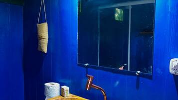 Un baño con un lavamanos de madera, paredes azules y un espejo.