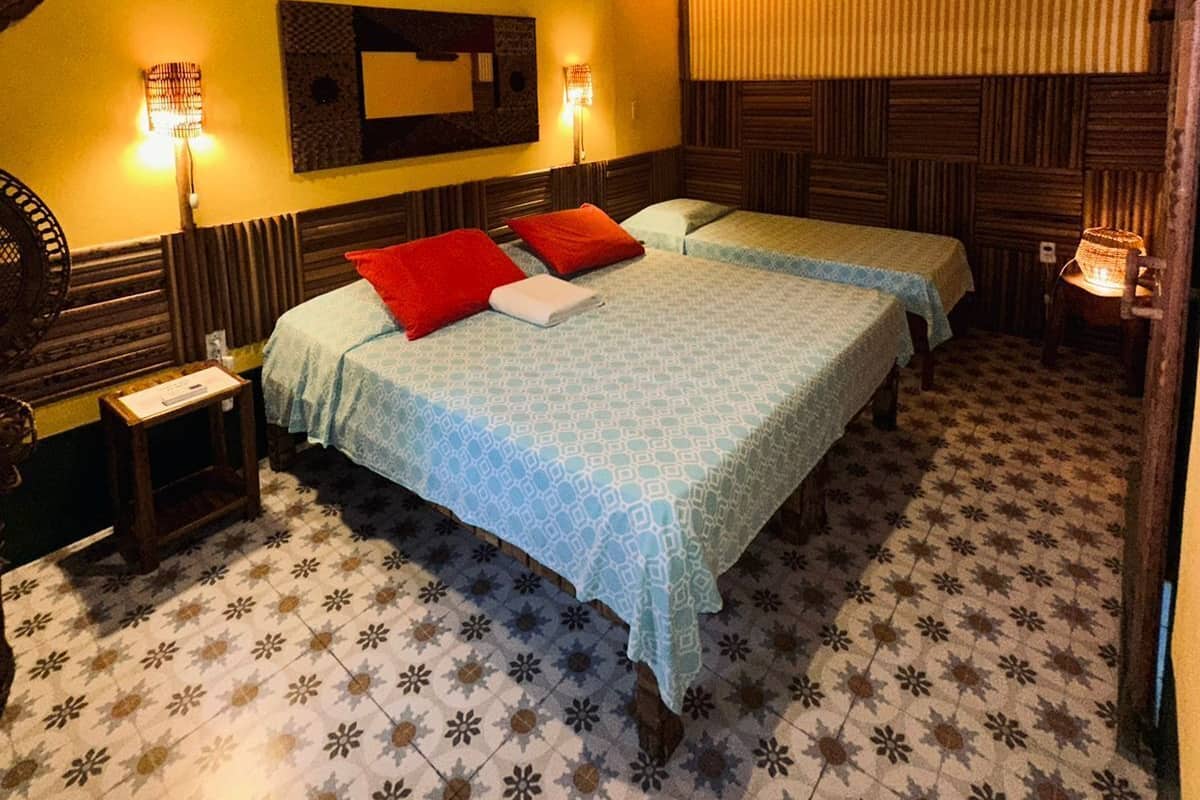 Une chambre avec deux lits, un plafond en bois, une décoration solaire sur le mur et des carreaux de sol à motifs.