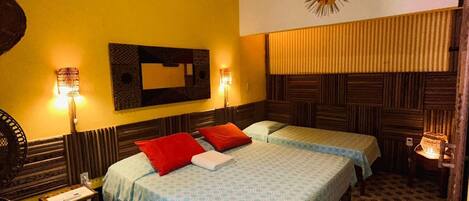 A room with two beds, a wooden ceiling, a sun decoration on the wall, and patterned floor tiles.