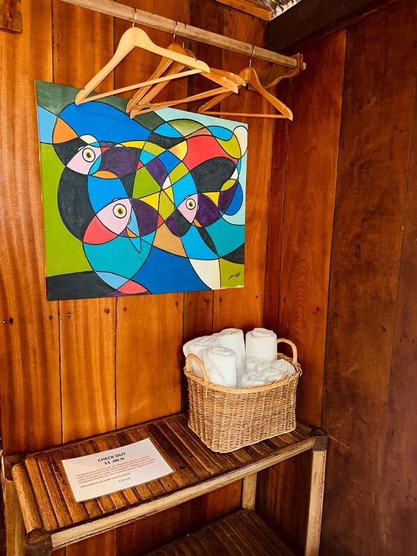 Un mur en bois orné d’un tableau abstrait aux couleurs vives et un panier en osier contenant des serviettes.