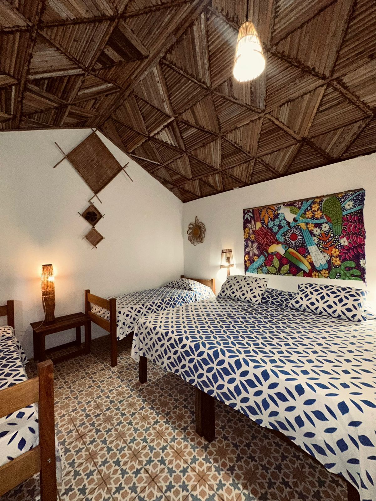 Una habitación con dos camas, piso estampado y techo de madera.