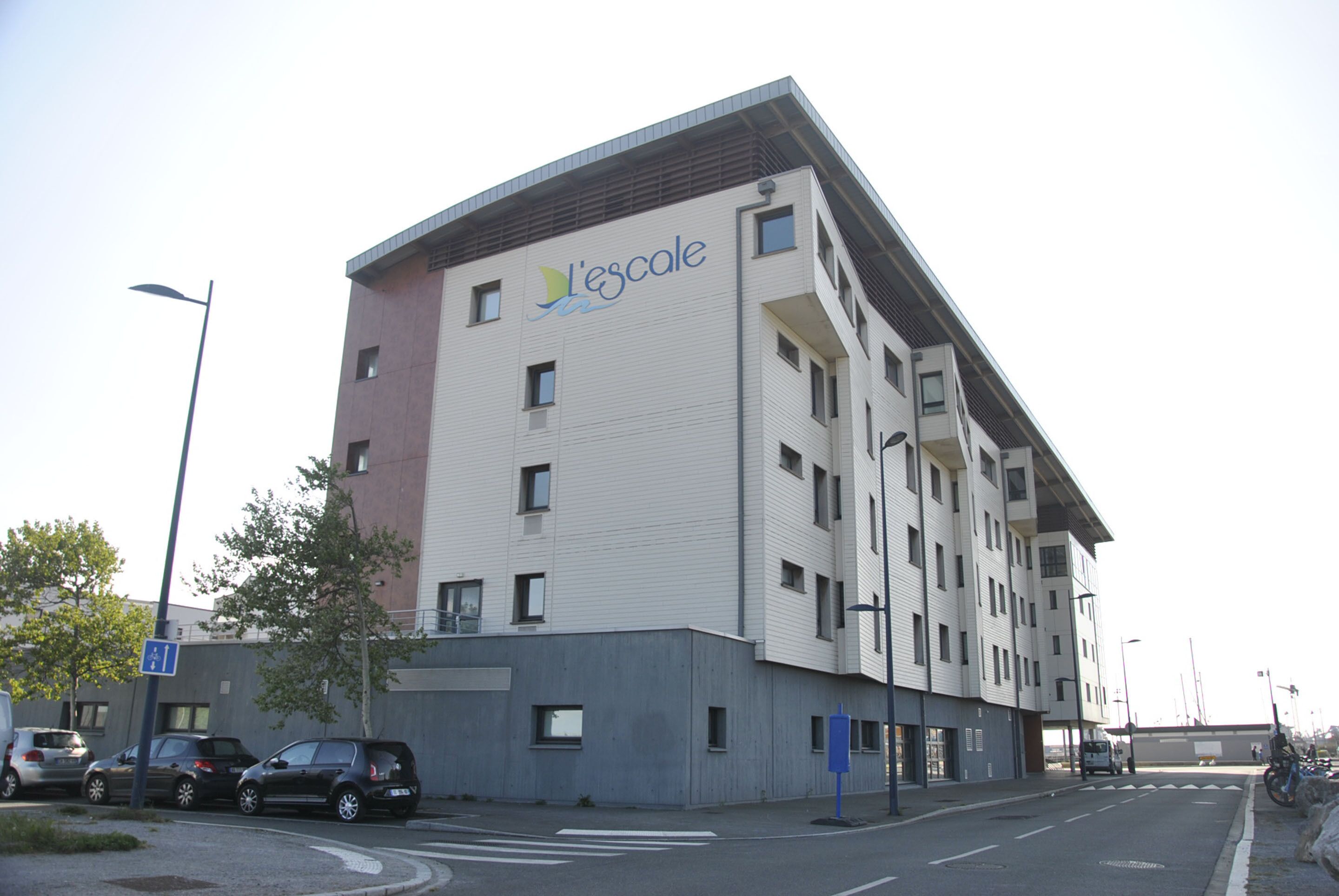 Un edificio de varios pisos con un diseño arquitectónico moderno, que presenta un logotipo destacado en la fachada.
