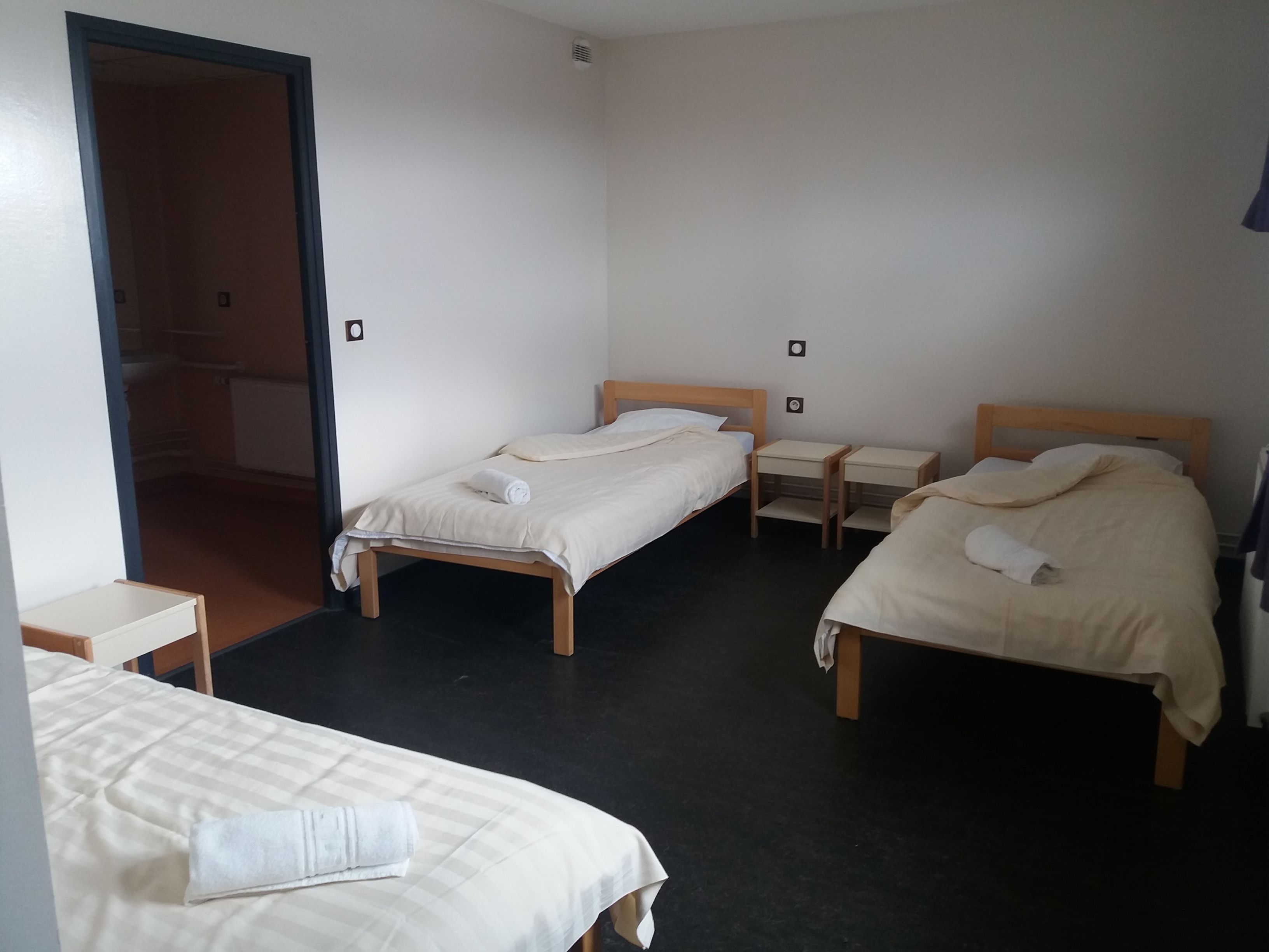 Een hotelkamer met twee enkele bedden, een tafeltje en een garderobe.