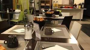 A dining area with tables set for breakfast, including croissants and coffee.