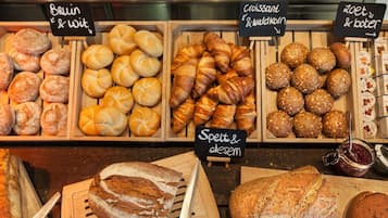 Eine Bäckerauslage mit verschiedenen Brotsorten und Gebäck, darunter Croissants, Brötchen und Mehrkornbrötchen.