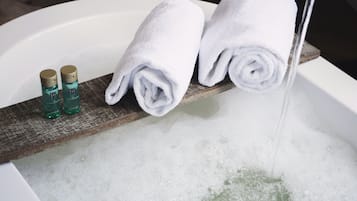 Una bañera con dos toallas enrolladas y dos botellas de productos de baño.