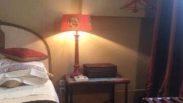 A bedroom with a bed, a bedside table with a lamp, a chair, and a patterned rug.
