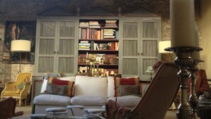 Uma sala de estar aconchegante com sofá, poltronas, estante e lareira.