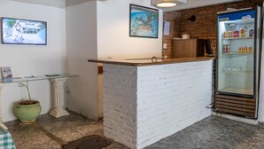 Un área de recepción con mostrador de ladrillo blanco, una vitrina de vidrio, un mapa en la pared y un refrigerador lleno de bebidas.