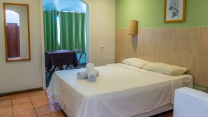 Habitación de hotel con cama, una mesa con sillas, cortina verde y un cuadro en la pared.