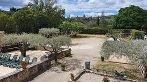 Un patio con mobiliario exterior, paredes de piedra y diversas especies de árboles.
