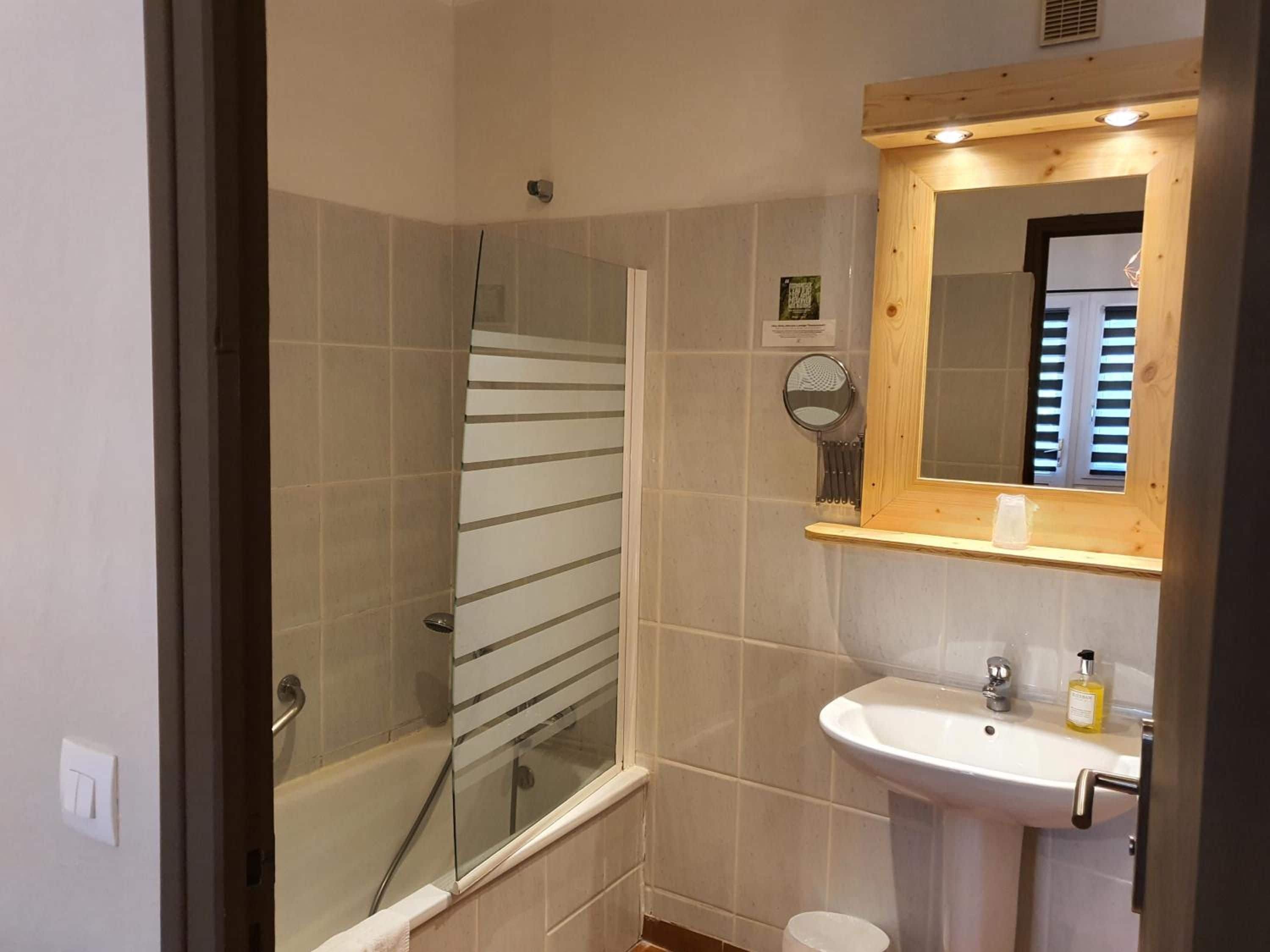 A bathroom with a glass shower enclosure, a sink with a mirror above it, and a toilet.