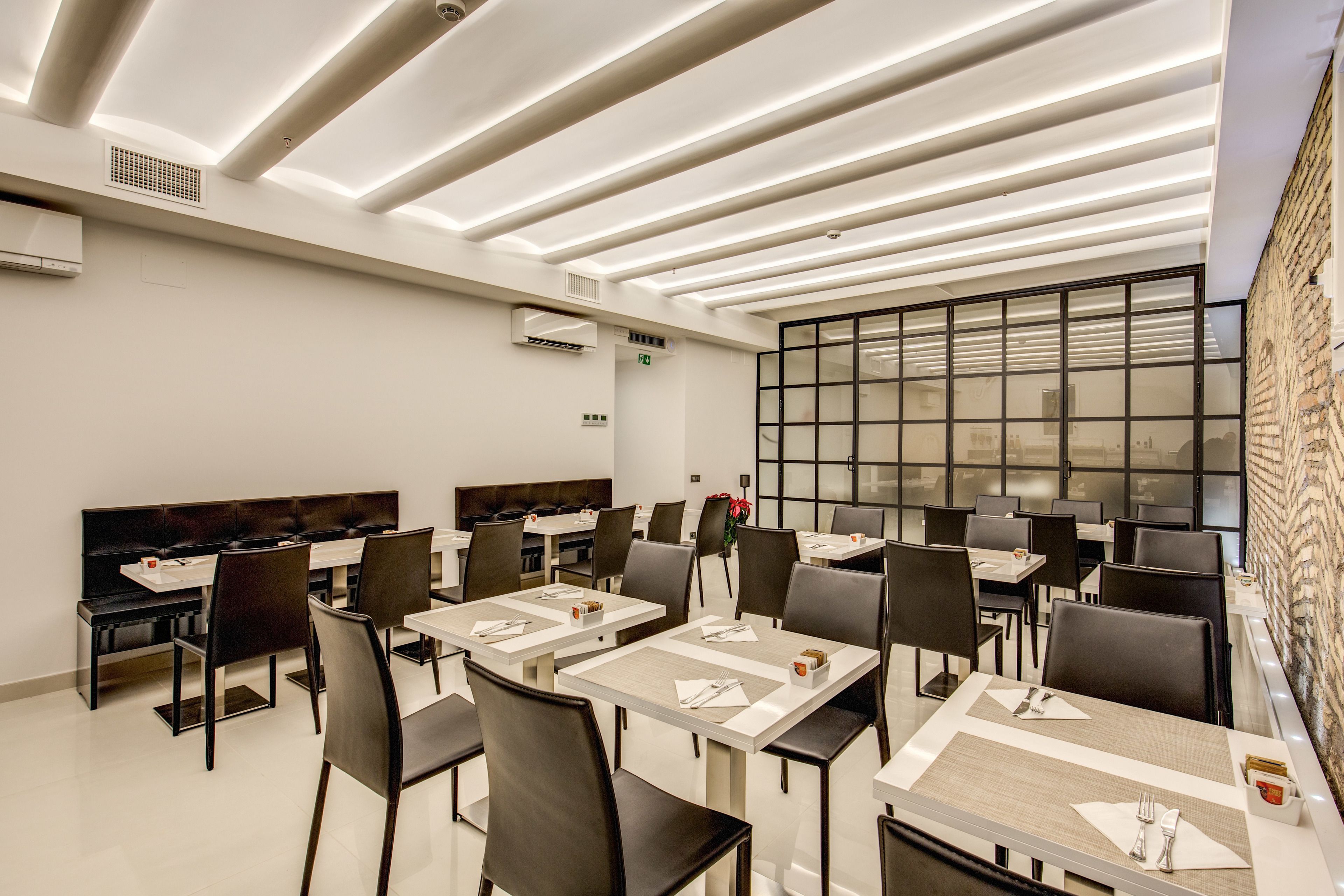 A modern dining area with multiple tables and chairs, a large window with a view, and a unique ceiling design.