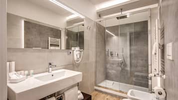 Een moderne badkamer met een ruime wastafel, een douche met glazen wanden en een apart bad.