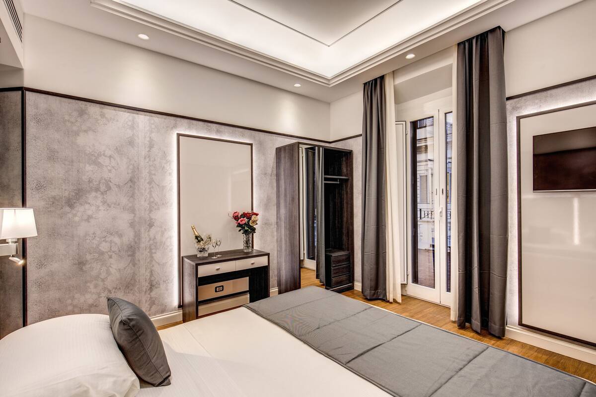 A modern bedroom with a bed, bedside table, and a large mirror.
