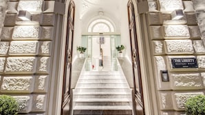 Una imponente escalera que conduce a una habitación con un cartel que dice 'The Liberty Boutique Hotel'.
