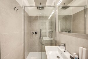 A modern bathroom with a glass-enclosed shower, a large sink, and a mirror.