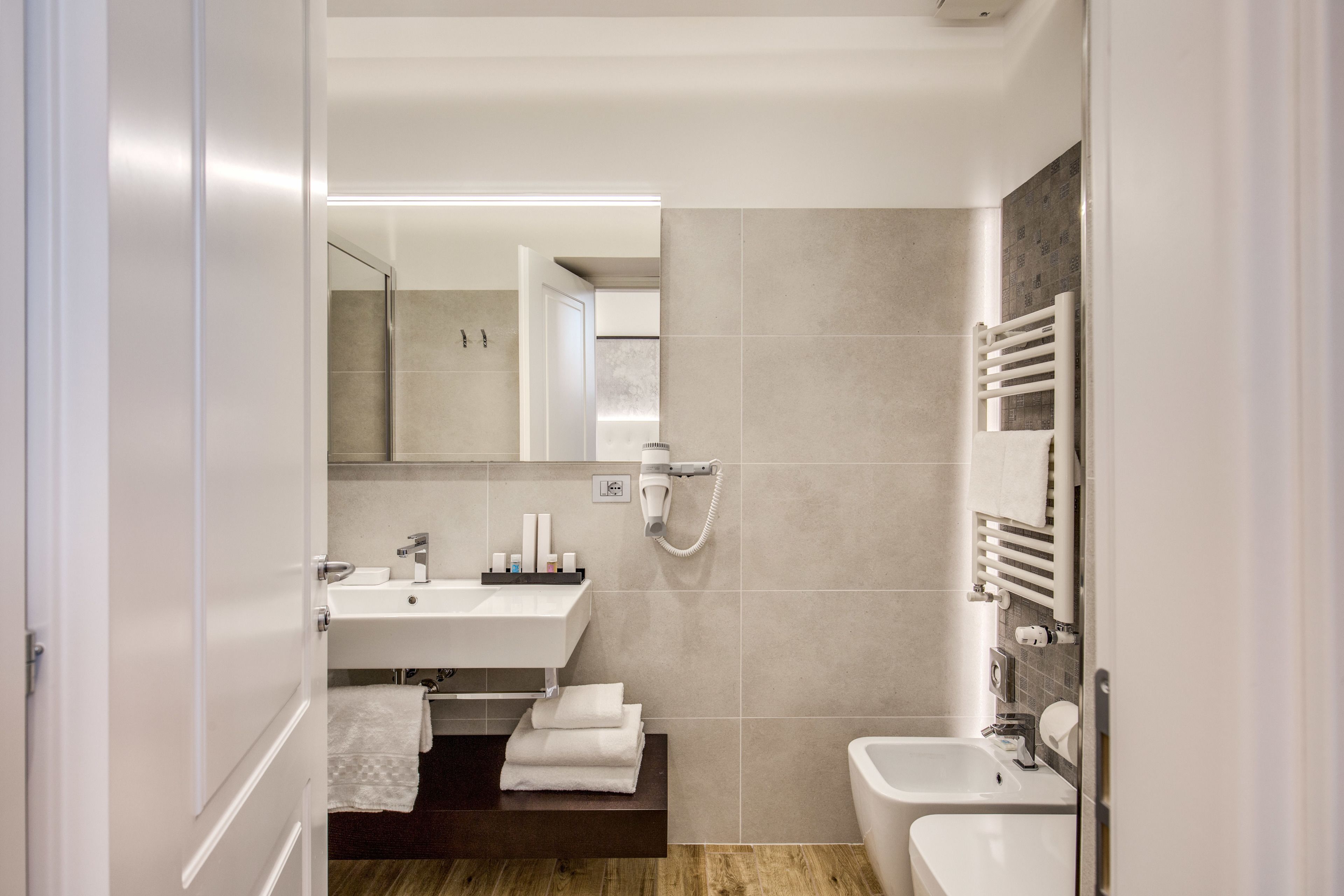 Uma casa de banho moderna com lavatório, espelho, toalheiro e chuveiro.