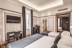 A modern hotel room with two beds, a desk, a TV, and a wardrobe.