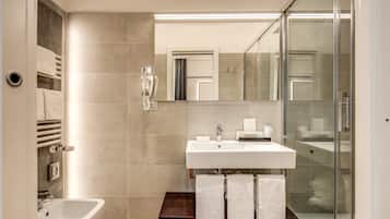 Et moderne badeværelse med en hvid vask, et glasbadeværelsesafskærmning og en bidet.