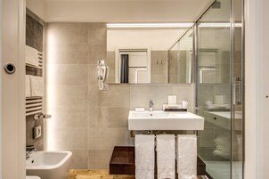 Et moderne badeværelse med en hvid vask, et glasbadeværelsesafskærmning og en bidet.
