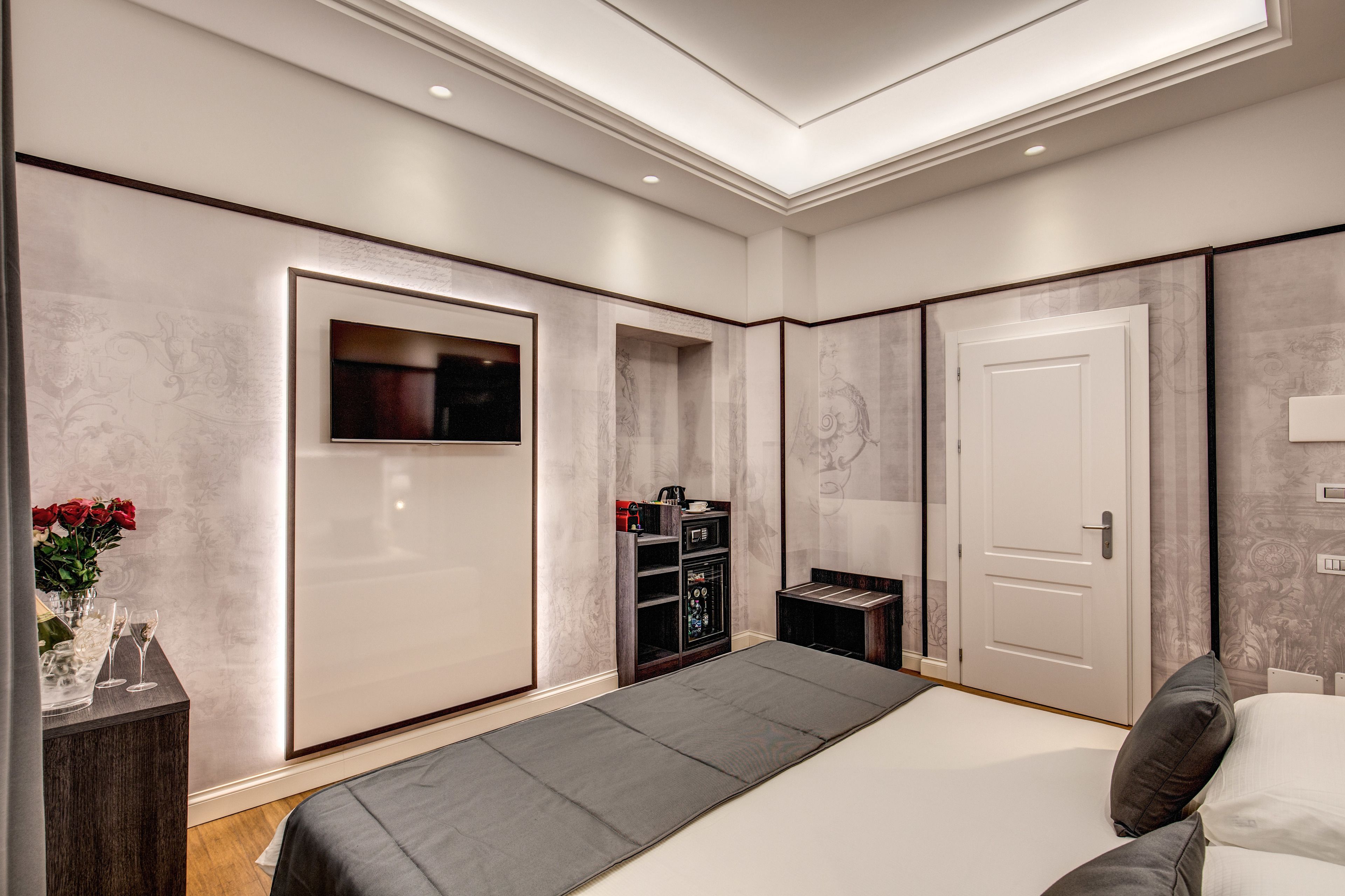 Ein modernes Schlafzimmer mit einem großen Bett, einem an der Wand montierten Fernseher und einem Kleiderschrank.