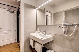 Un baño moderno con un lavamanos blanco, un secador de pelo y un perchero para toallas.