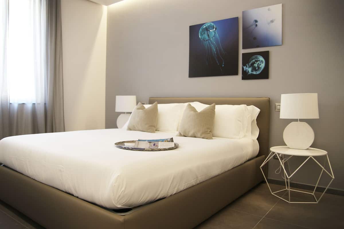 Una habitación de hotel moderna con una cama grande, dos mesitas de noche y una obra de arte en la pared.