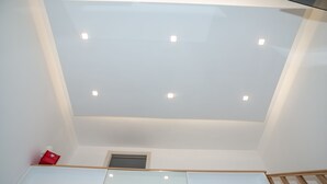 A modern interior with a skylight, recessed lighting, and a wooden staircase.