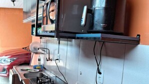 Una cocina compacta con estufa a gas, cafetera y un lavamanos pequeño.
