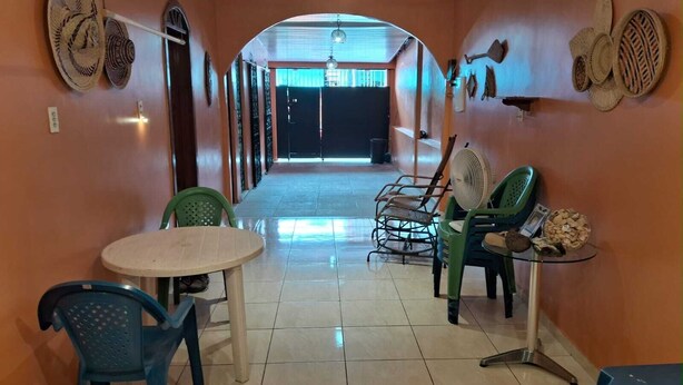 Un pasillo con una mesa redonda, sillas, un ventilador y objetos decorativos en las paredes.